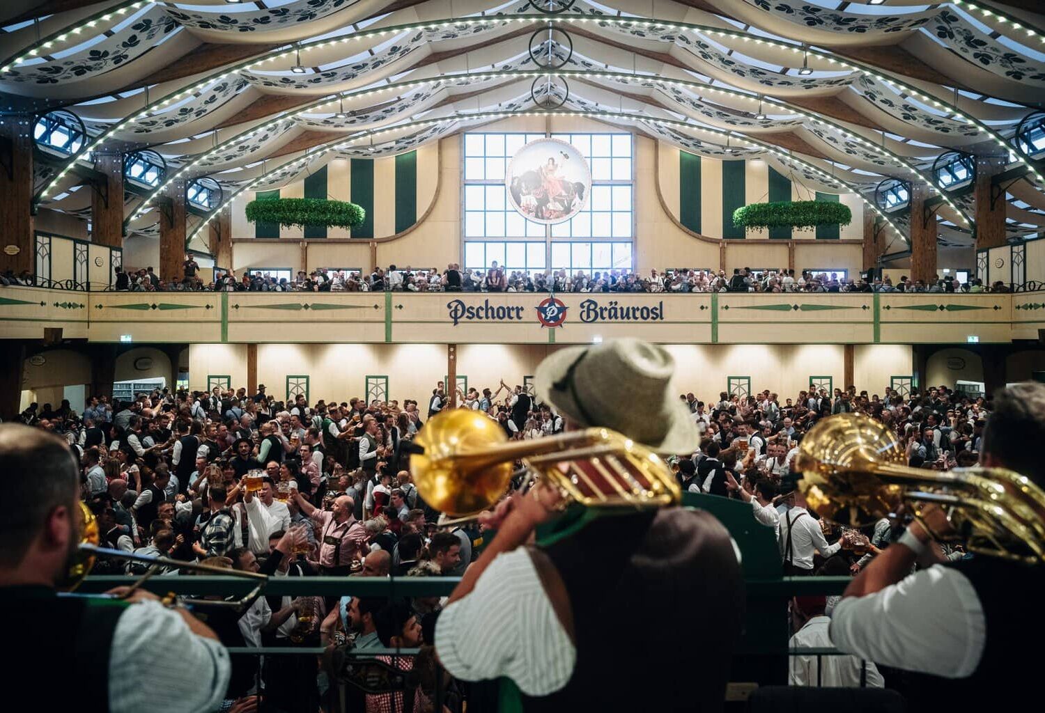 Muzikanten met trombones spelen boven de menigte in de feesttent Pschorr-Bräurosl op het Oktoberfest in München
