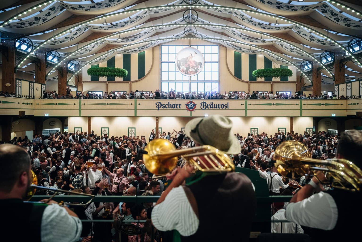 Muzikanten met trombones spelen boven de menigte in de feesttent Pschorr-Bräurosl op het Oktoberfest in München