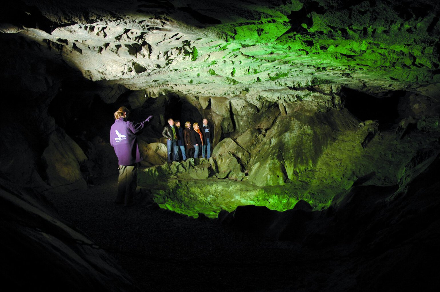 Rondleiding in de Kalkberggrot in Bad Segeberg: een gids wijst een groep in de groen verlichte grotzaal op de rotsformaties.