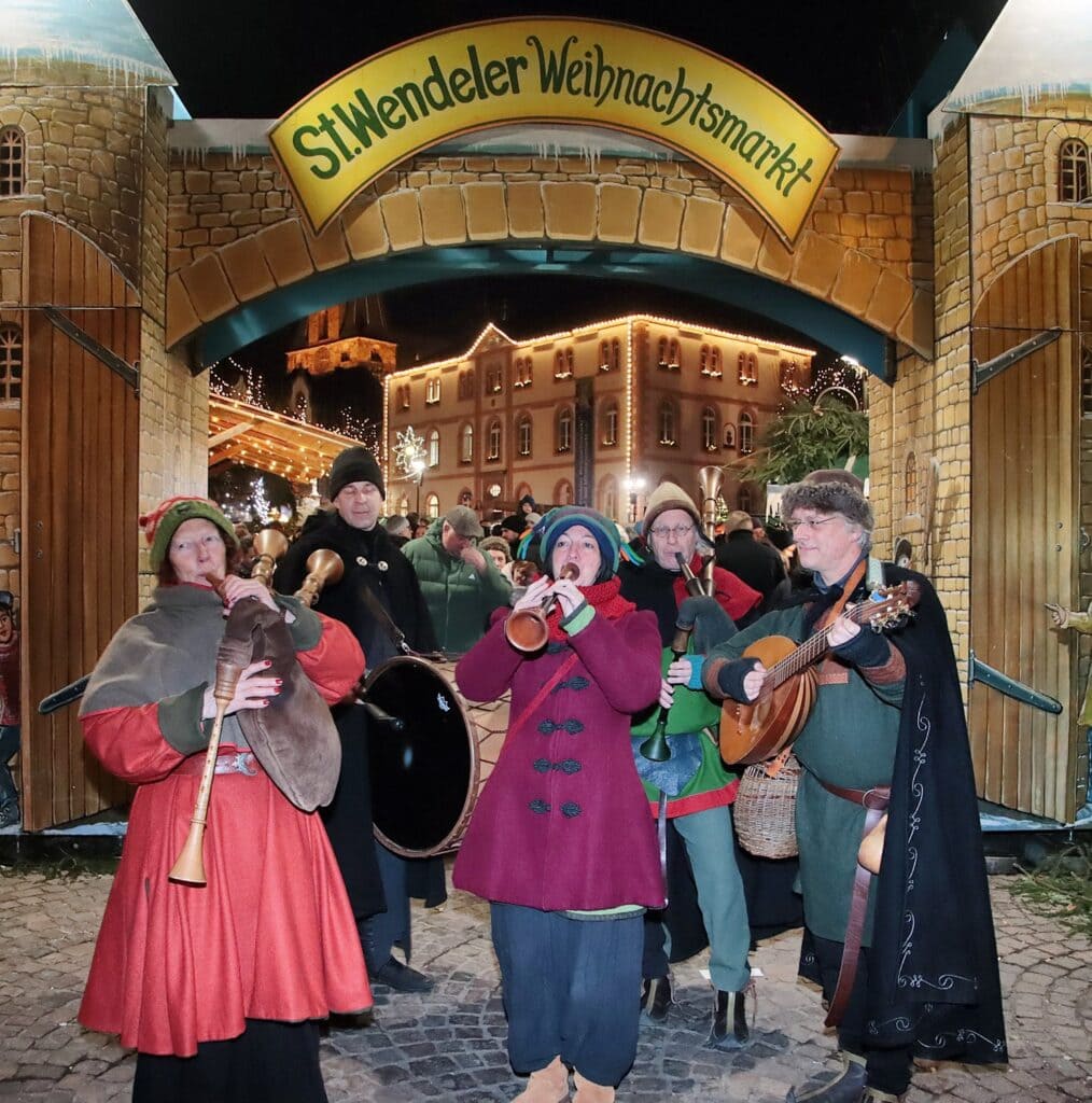 Middeleeuwse muzikanten met doedelzakken en luit spelen bij de ingangspoort van de St. Wendeler Weihnachtsmarkt