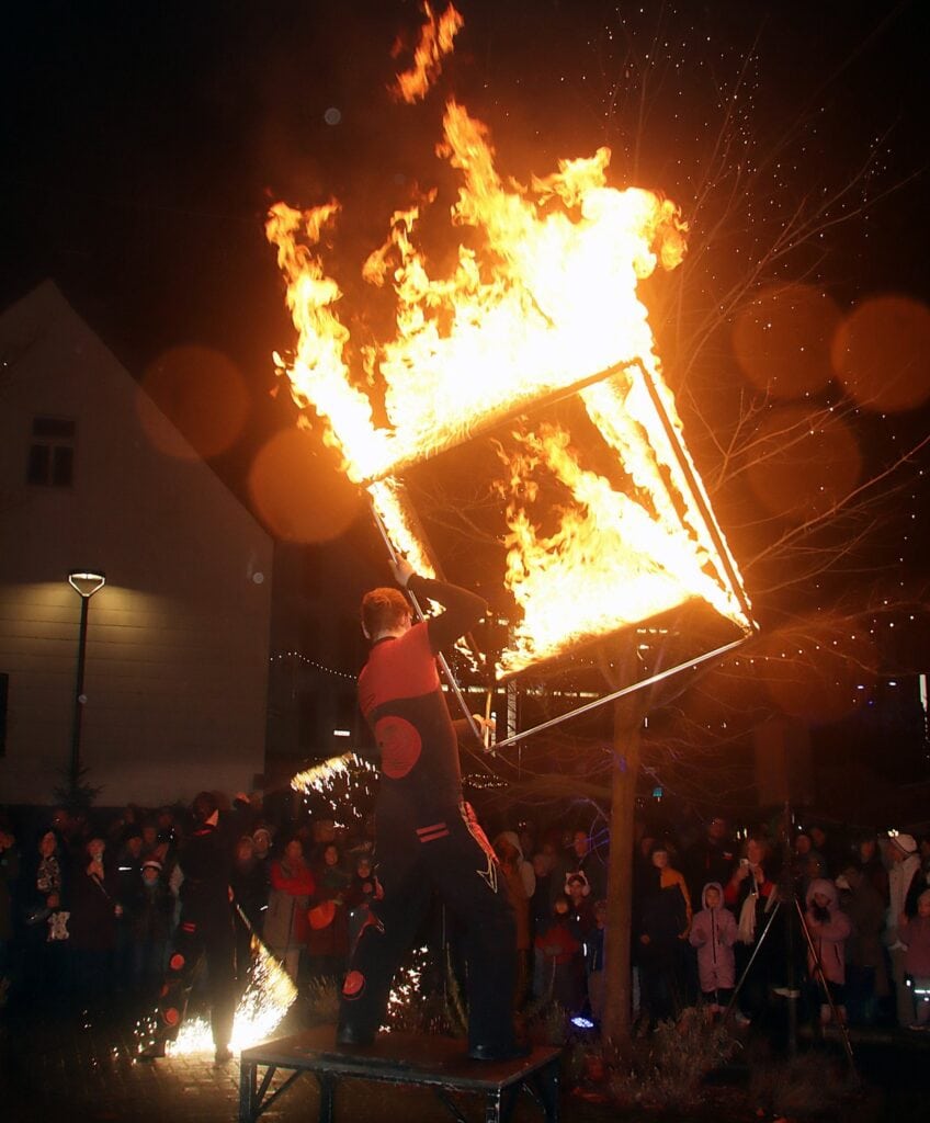 Vuurartiest zwaait 's avonds met een brandende kubus boven het publiek op de kerstmarkt van St. Wendel